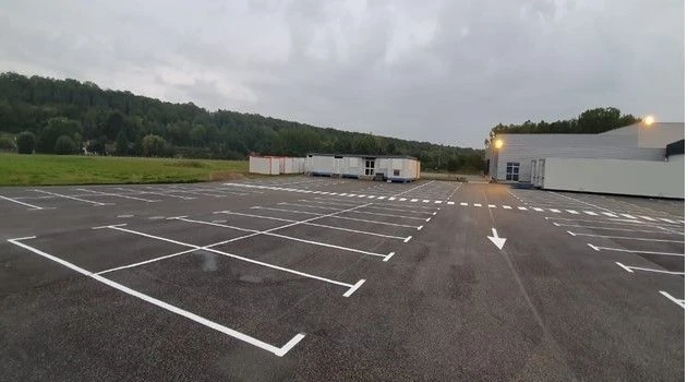 Allée d'accès privative fraîchement bitumée, vue en perspective centrale, bordures béton préfabriquées de type caniveau