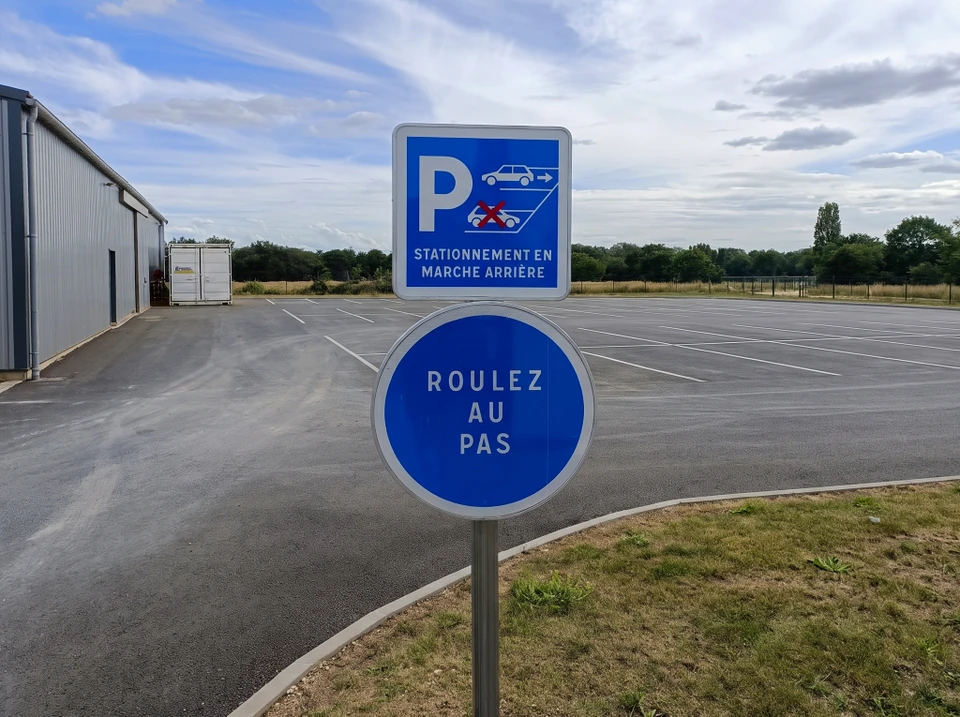 Marquage au sol d'interdiction de stationnement : cercle rouge avec croix bleue peint sur bitume