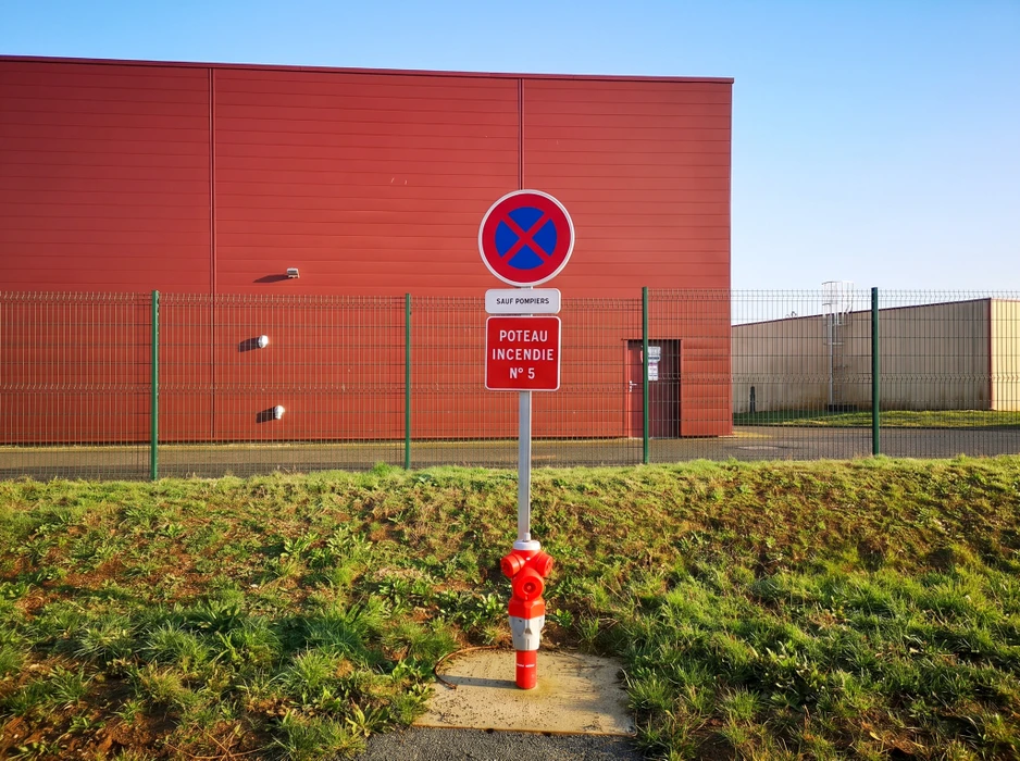 Zone commerciale en plein air avec parking bitumé quasi-vide, marquage au sol blanc