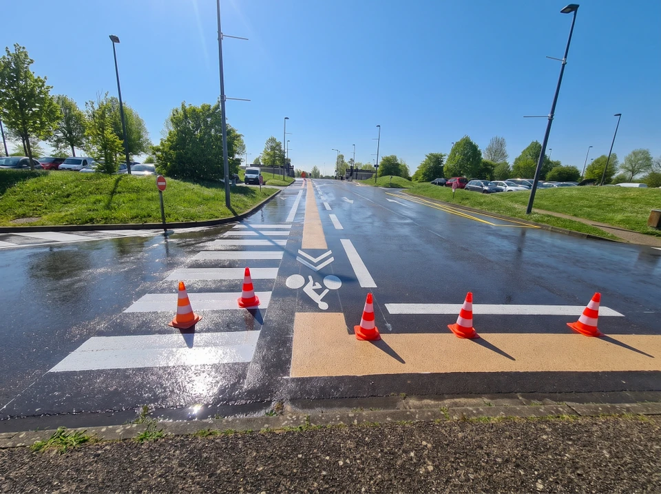 Passage piéton en marquage au sol blanc, vue en perspective sur voirie asphaltée en courbe